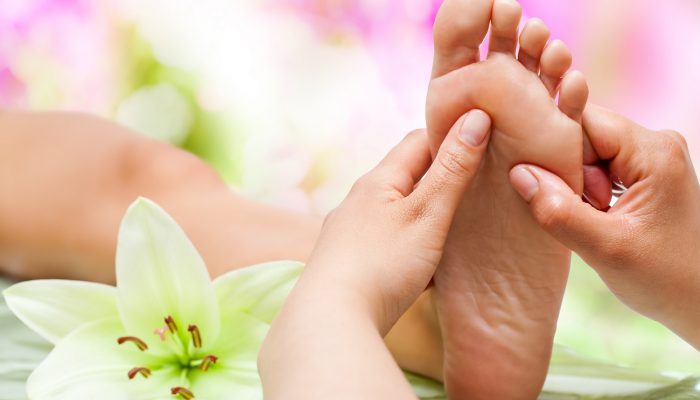 Close up of therapist's hands massaging female foot.